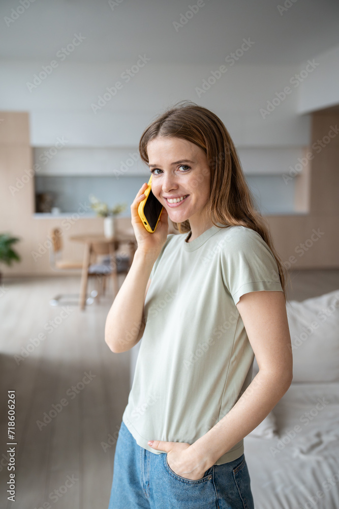 Happy cheerful middle-aged woman speaking over mobile phone at home, making, answering call, having pleasant funny conversation with friend, parents, smiling friendly with teeth looking at camera Happy cheerful middle-aged woman speaking over mobile phone at home, making, answering call, having pleasant funny conversation with friend, parents, smiling friendly with teeth looking at camera
