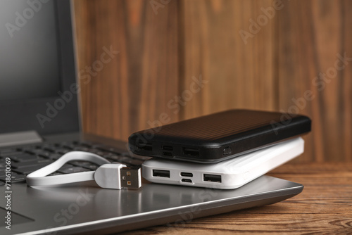 Laptop with power banks external battery on wooden background