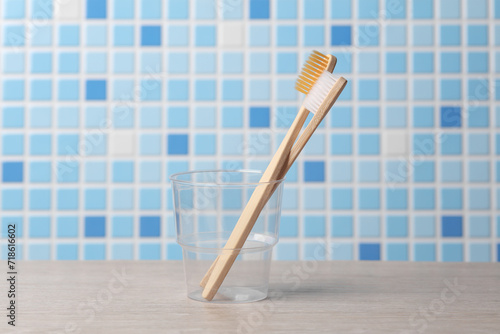 Two bamboo toothbrushes in a transparent glass in the bathroom