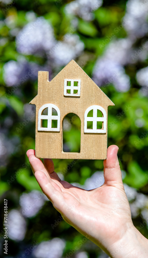 The girl holds in her hand the symbol of the house against the background of blooming lilac
The girl holds in her hand the symbol of the house against the background of blooming lilac