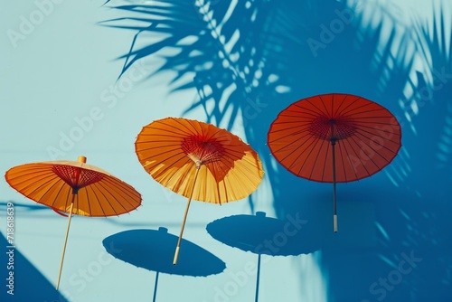 Trio of Traditional Asian Paper Umbrellas Casts Elegant Shadows on Blue Background  Ideal for Cultural and Design Themes