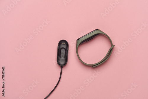 Smart bracelet with charger on pink background photo