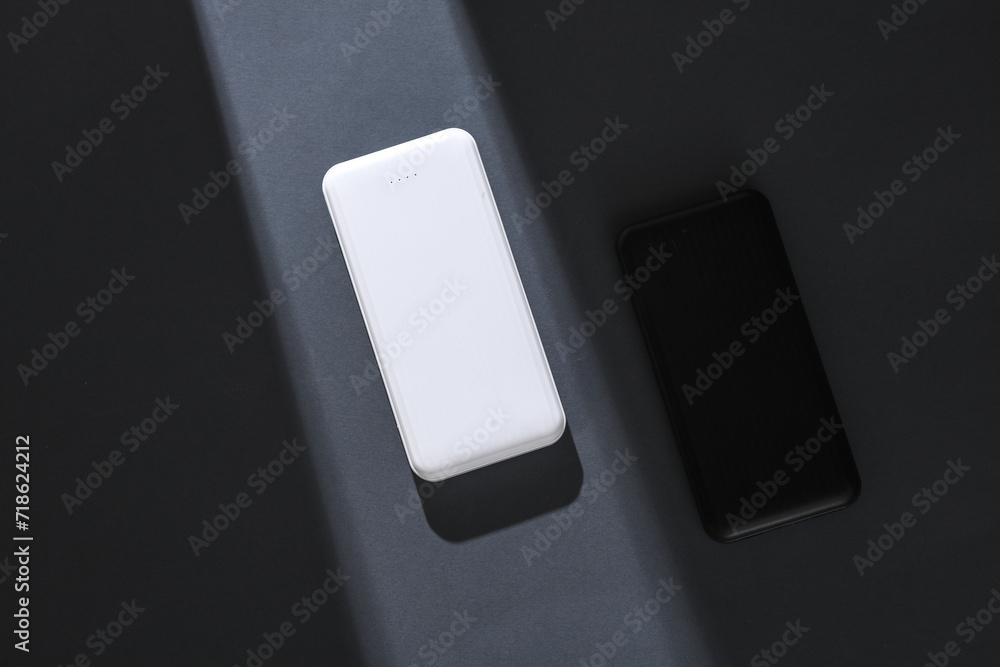 Power banks on gray background with stripe of light and shadow. Minimalism. Concept photo Power banks on gray background with stripe of light and shadow. Minimalism. Concept photo