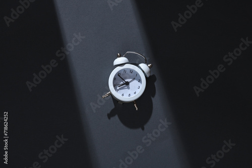 Alarm clock on gray background with stripe of light and shadow. Minimalism. Concept photo