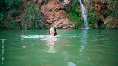 Naked woman swimming lagoon in beautiful summer nature. Lady splashing in lake