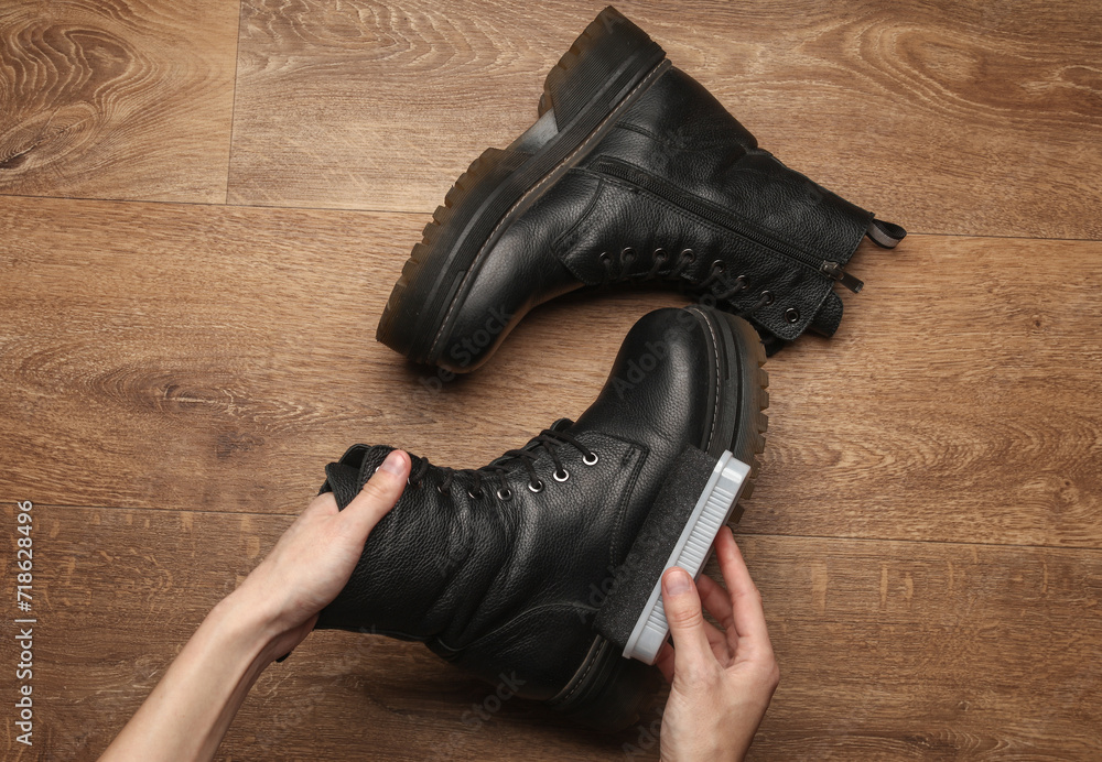 Hands applying shoe polish to black leather boots - obrazy, fototapety, plakaty 
