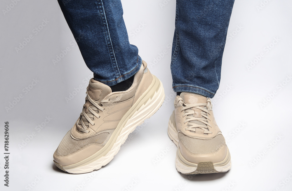 Male legs in jeans and sneakers on a white background Male legs in jeans and sneakers on a white background