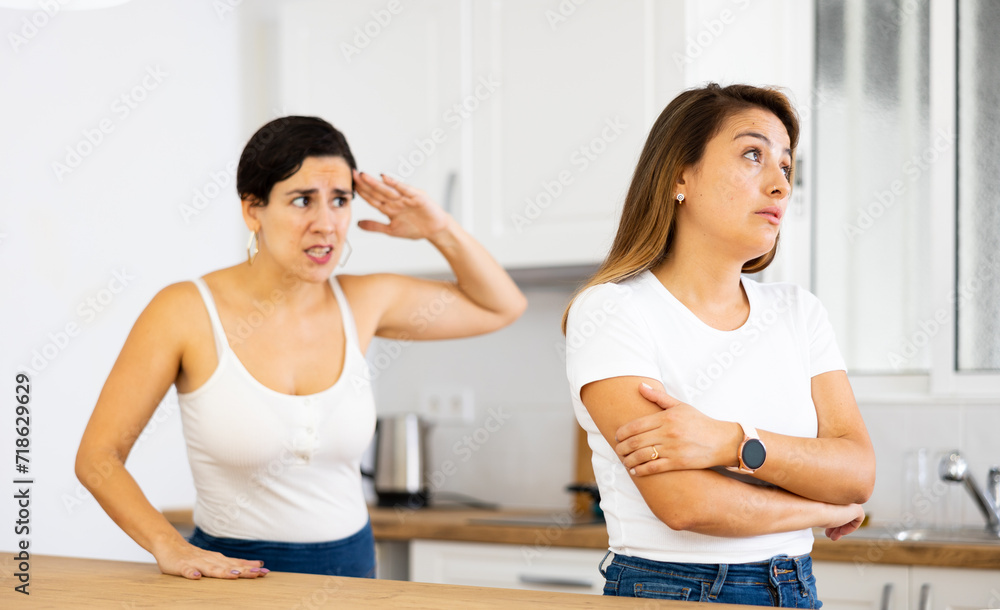 Offended scornful young latin american woman listening to angry and dissatisfied female friend, emotionally gesturing and voicing her displeasure. LGBT couple relationship concept..