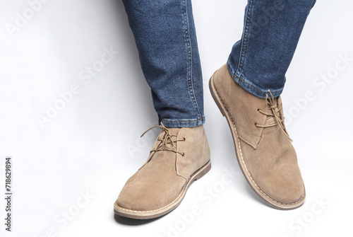 Male legs in jeans and desert shoes on a white background