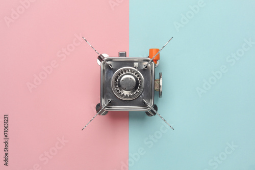 Portable camping gas burner on a blue-pink pastel background photo