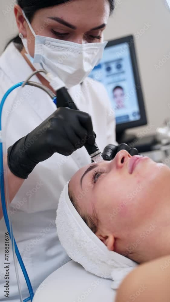 Esthetician performs hydrafacial on client using high tech hydro dermabrasion device for skin rejuvenation in clinic. Hydra facial treatment offers exfoliation, acne reduction and anti-aging benefits. Esthetician performs hydrafacial on client using high tech hydro dermabrasion device for skin rejuvenation in clinic. Hydra facial treatment offers exfoliation, acne reduction and anti-aging benefits.