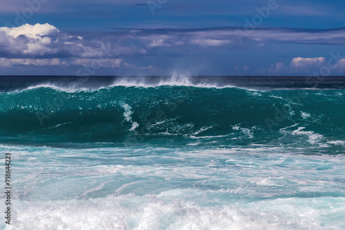 Large wave breaking offshore, Kona coast, Big island of Hawaii. Blue sky and clouds in background. 