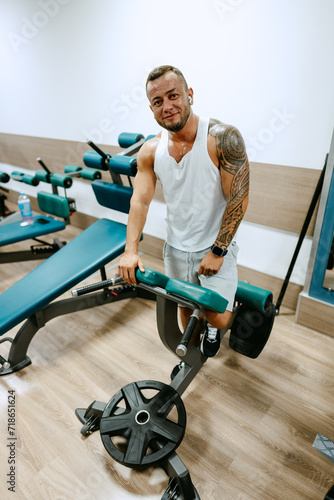 Man bodybuilder in white shirt training in a gym