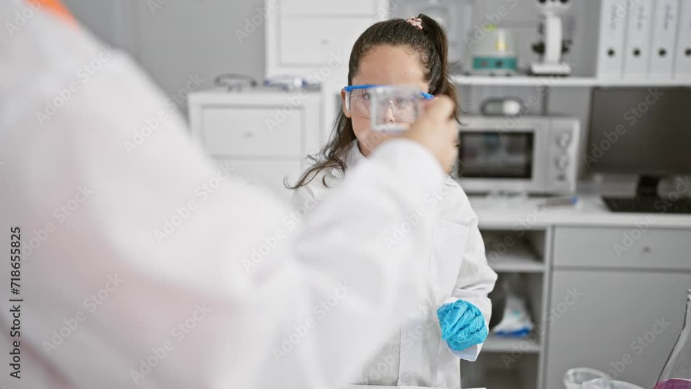 Two dedicated scientists, working intensely together in a laboratory, safe behind their glasses, immersed in test tube analysis. Two dedicated scientists, working intensely together in a laboratory, safe behind their glasses, immersed in test tube analysis.