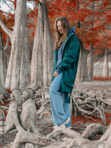 Woman walk down the park among tacsodium trees. People in autumnal forest. photo