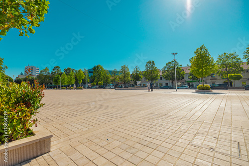 Trg Slobode or freedom square in the centre of Niksic, Montenegro on a sunny day. Flat open space in the centre of a city, surrounded by trees and foliage. photo