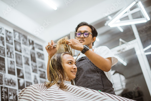 Fototapeta Naklejka Na Ścianę i Meble -  asian young customer excited for getting haircut from male barber
