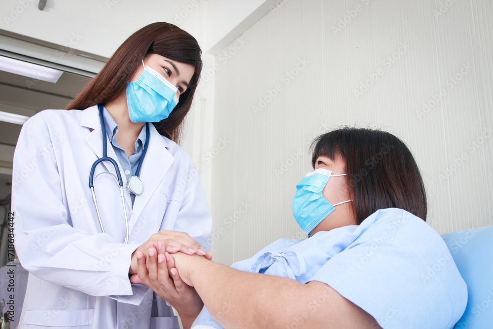 Asian female doctor holding hands with patient to encourage treatment. Disease rates for obese people such as high blood pressure, hypercholesterolemia, diabetes. Medical services Asian female doctor holding hands with patient to encourage treatment. Disease rates for obese people such as high blood pressure, hypercholesterolemia, diabetes. Medical services