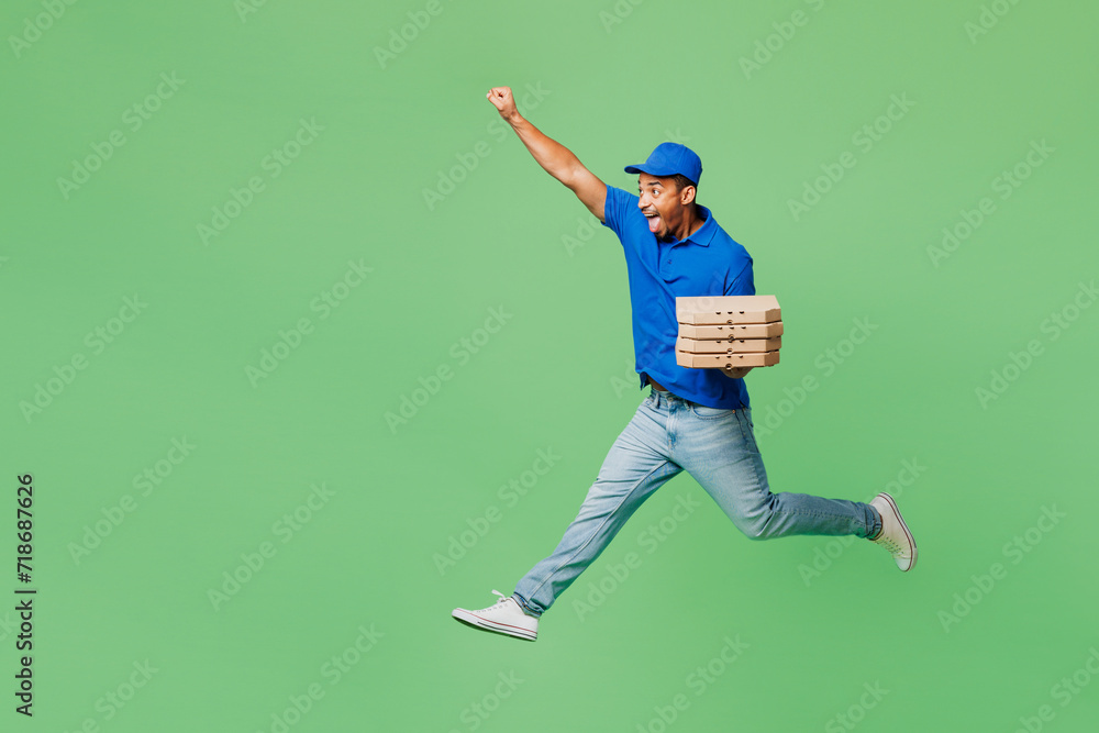 Delivery employee man wear blue cap t-shirt uniform workwear work as dealer courier jump high hold stack of pizza in flatbox do super hero gesture isolated on plain green background Service concept. Delivery employee man wear blue cap t-shirt uniform workwear work as dealer courier jump high hold stack of pizza in flatbox do super hero gesture isolated on plain green background Service concept.