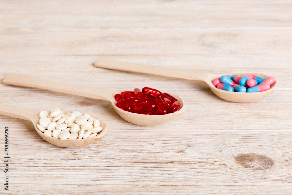 Vitamin capsules in a spoon on a colored background. Pills served as a healthy meal. Red soft gel vitamin supplement capsules on spoon Vitamin capsules in a spoon on a colored background. Pills served as a healthy meal. Red soft gel vitamin supplement capsules on spoon