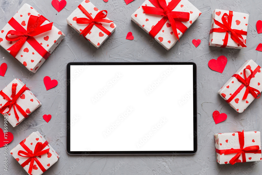 Top view of digital tablet with gift boxes and hearts on colorful background. Tablet with black screen with Holiday decorations gift box top view Top view of digital tablet with gift boxes and hearts on colorful background. Tablet with black screen with Holiday decorations gift box top view