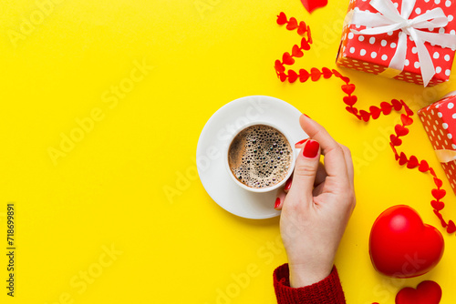 Flat lay of heart shaped cup of black coffee in the hands of women on colored background with copy space top view. Valentine day and holiday concept