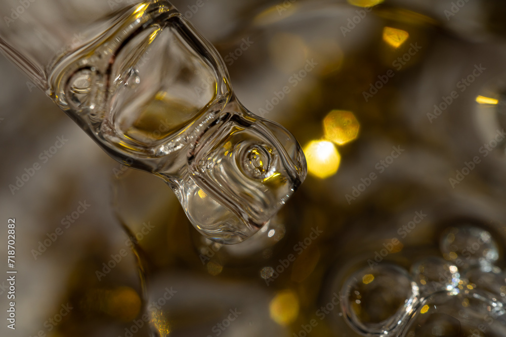 A drop of cosmetic aromatic oil drips from the pipette. Front view. A drop of cosmetic aromatic oil drips from the pipette. Front view.