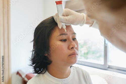 Young asian woman undergoing eyebrow correction procedure in beauty salon, closeup