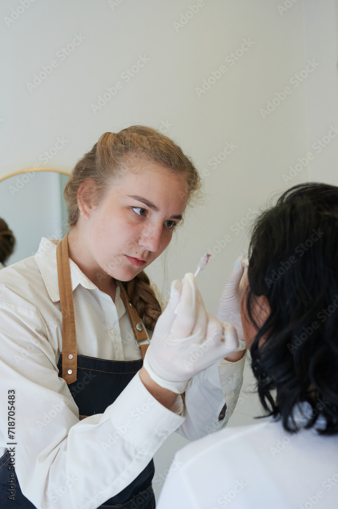 Obraz premium Beautiful young woman gets eyebrow correction procedure