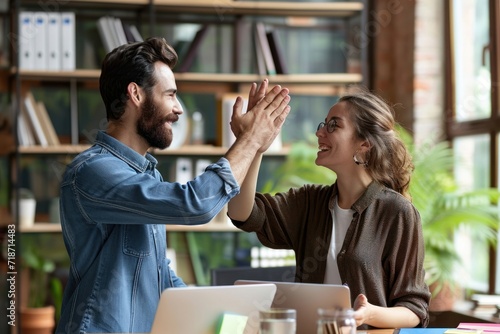 Two happy friendly diverse professionals, teacher and student giving high five standing in office celebrating success, partnership teamwork and team motivation in office, Generative AI photo