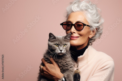 Happy senior lady with cat on beige background. Human and pet.
