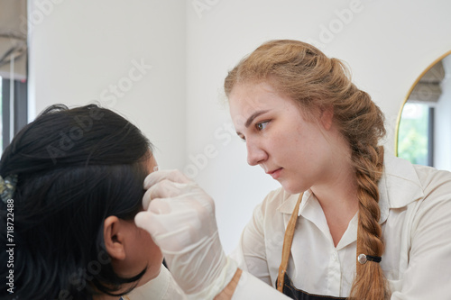 Young Asian woman undergoing eyebrow correction procedure in beauty salon  closeup