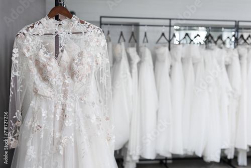 Many luxurious expensive wedding dresses are hanging on hangers in the wedding salon, shop. © Artem Zakharov