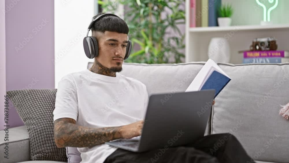 Hardworking young latin man deep in thought, studying with laptop and headphones from the cozy corner of his home living room Hardworking young latin man deep in thought, studying with laptop and headphones from the cozy corner of his home living room
