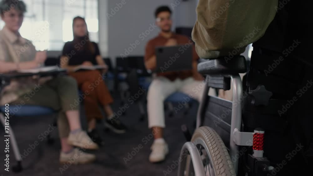 Cropped back view shot of unrecognizable wheelchaired business coach giving lecture to diverse group of people listening to him Cropped back view shot of unrecognizable wheelchaired business coach giving lecture to diverse group of people listening to him