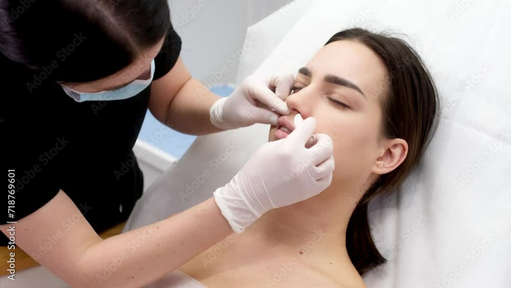 Cosmetology clinic, the doctor applies anesthesia to the patient's lips, anesthetic before injecting hyaluronic acid. Anesthetic ointment is applied before the injection procedure. Cosmetology clinic, the doctor applies anesthesia to the patient's lips, anesthetic before injecting hyaluronic acid. Anesthetic ointment is applied before the injection procedure.