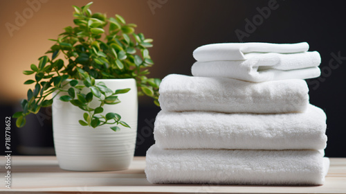 Stack of bath towels and vase with green plant