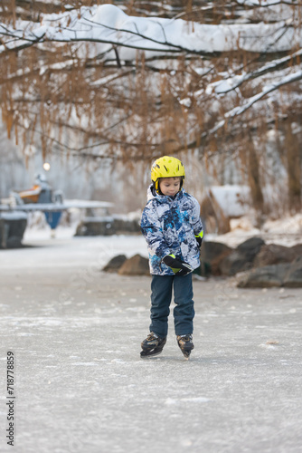 Happy child, boy, skating during the day on frozen lake, having fun