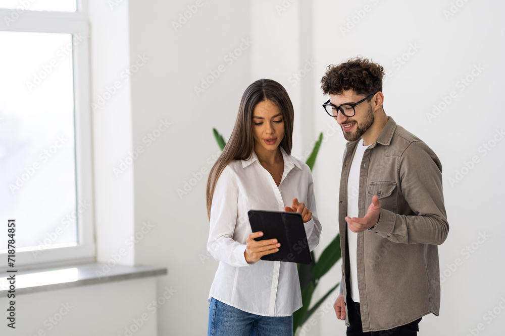 Two young businesspeople using a digital tablet while standing in a boardroom. Two young businesspeople using a digital tablet while standing in a boardroom.