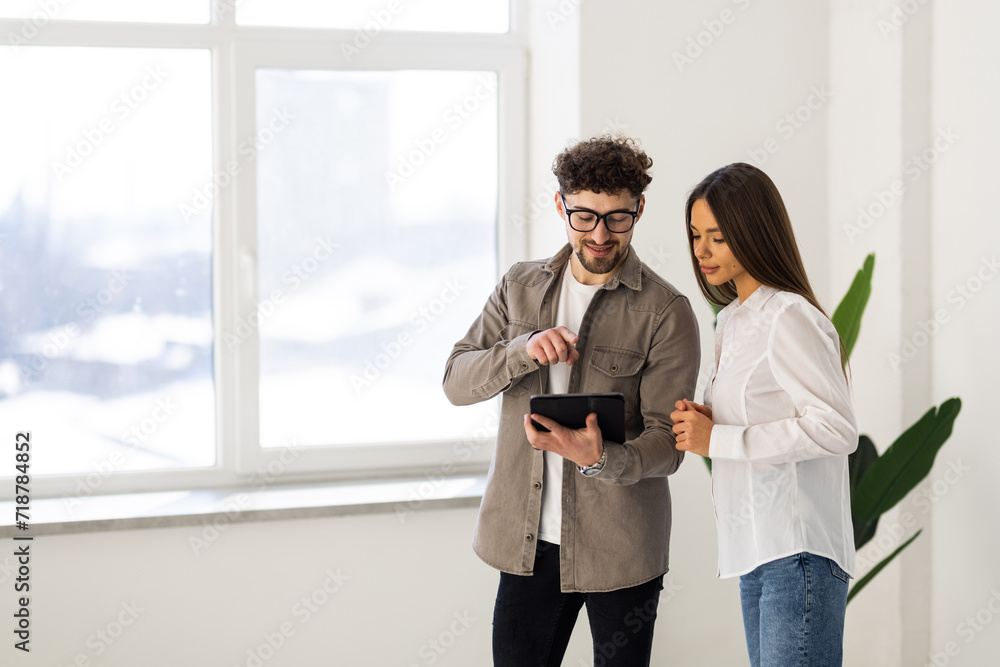 Fototapeta premium Two young businesspeople using a digital tablet while standing in a boardroom.
