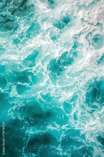 Vertical From above aerial view of turquoise ocean water with splashes and foam for abstract natural background and texture.