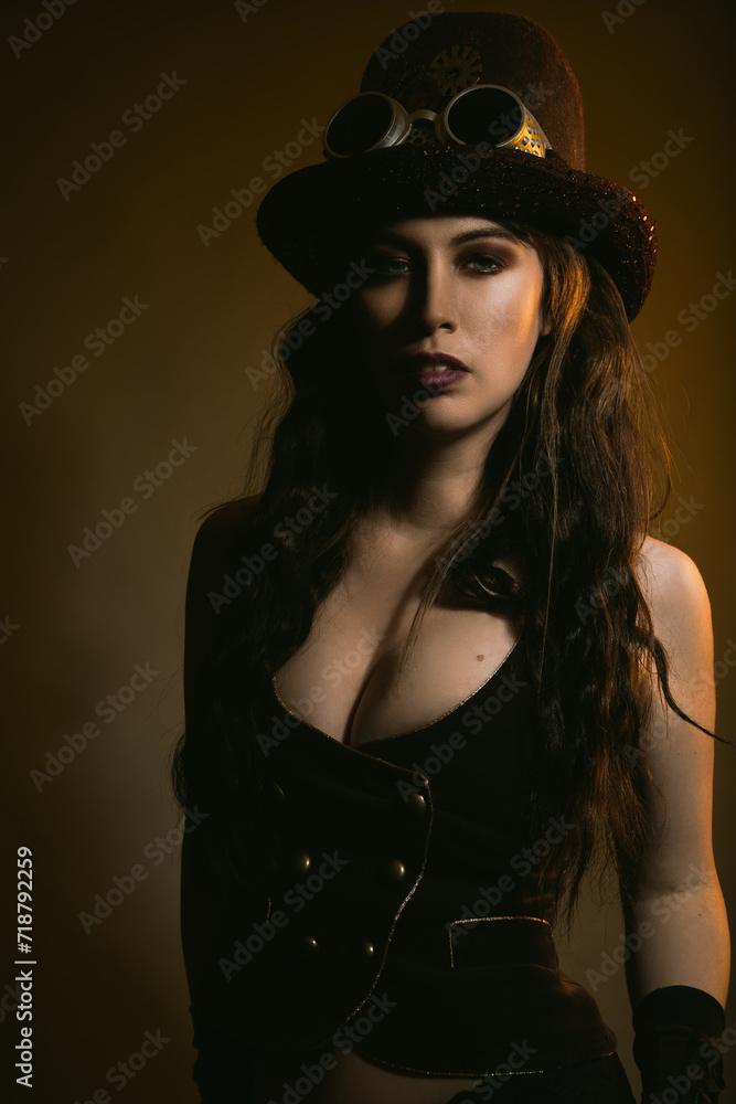 Studio portrait of a caucasian woman wearing steampunk fashion. She has long brown wavy hair and is wearing a steampunk hat. There is a golden tone to the portrait. Studio portrait of a caucasian woman wearing steampunk fashion. She has long brown wavy hair and is wearing a steampunk hat. There is a golden tone to the portrait.