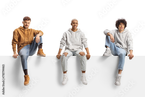 Photos African american guy sitting on a blank panel between caucasian guys