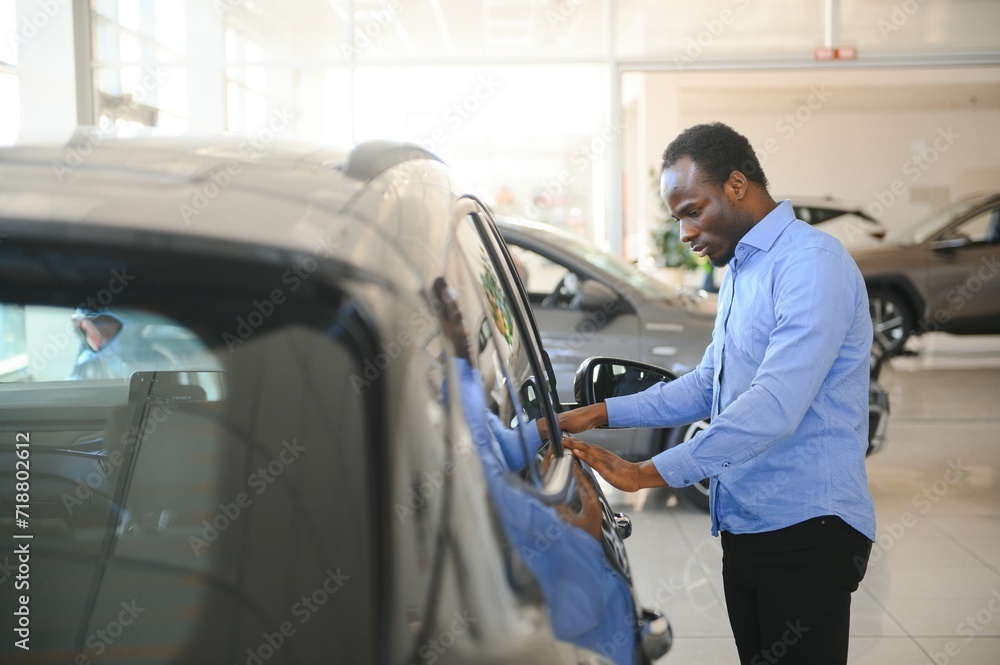 Handsome African man choosing a new car at the dealership Handsome African man choosing a new car at the dealership
