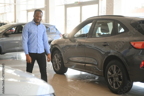 His dream car. Happy young African man looking excited choosing a car at the dealership © Serhii