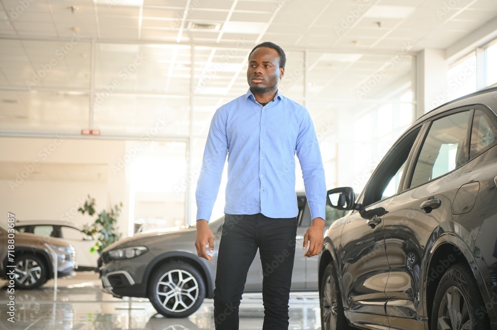 Handsome African man choosing a new car at the dealership Handsome African man choosing a new car at the dealership