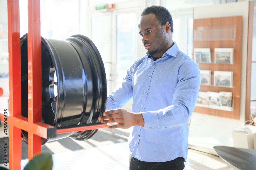 Obraz premium An African man buys car rims in an auto parts store