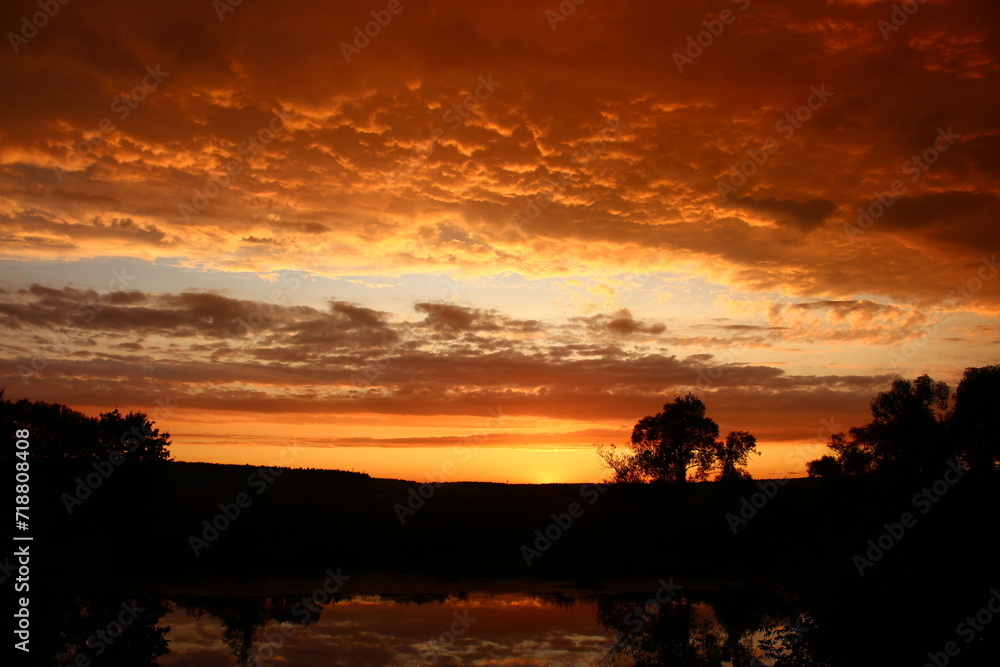 Colorful fiery sunset with a cloudy sky over the river, clouds painted in rich colors