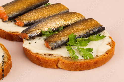 fish sandwiches. sandwiches made from white bread with mayonnaise and whole sprat fish sprinkled with parsley close-up, snack concept photo