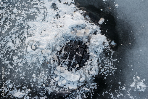 Car tire tread sticking out of the ice in the river